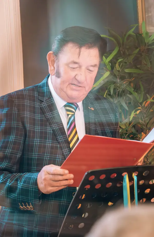 Greg Traynor reading from the red ceremony folder during a wedding ceremony