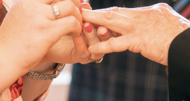 Bride and groom exchanging rings during a ceremony led by Greg